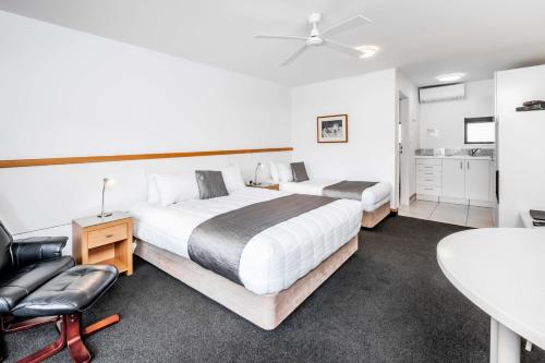 a bedroom with two beds and a table and a chair at Palms Motel in Nelson