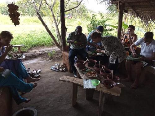 un grupo de personas sentadas alrededor de una mesa comiendo comida en Karu Homestay, en Sigiriya