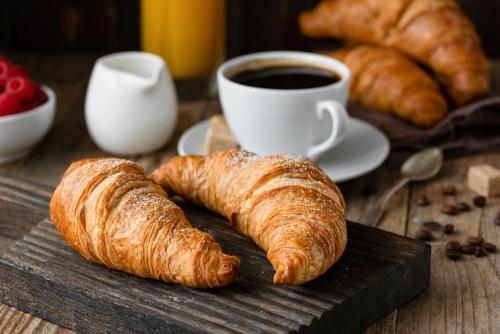 two croissants and a cup of coffee on a wooden table at Gypsea Bali in Uluwatu