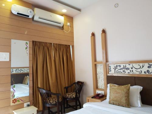 a bedroom with a bed and two chairs and a mirror at Hotel Temple On Ganges in Varanasi