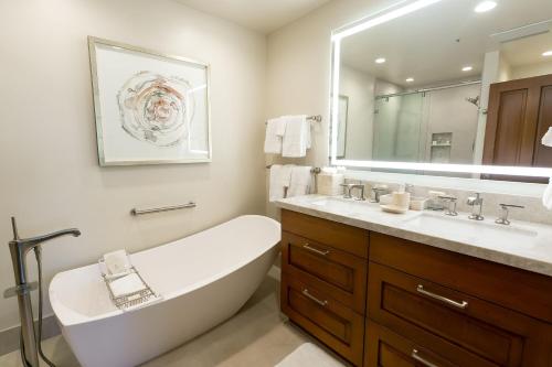 y baño con bañera, lavabo y espejo. en Deluxe Two Queen Room Hotel Room en Park City