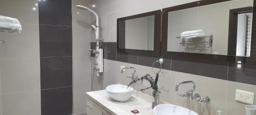 a bathroom with two sinks and two mirrors at Casa Boutique HNP in Barrancabermeja