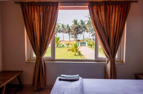 a bedroom with a large window with a view of the ocean at Sulo Villa in Malpe