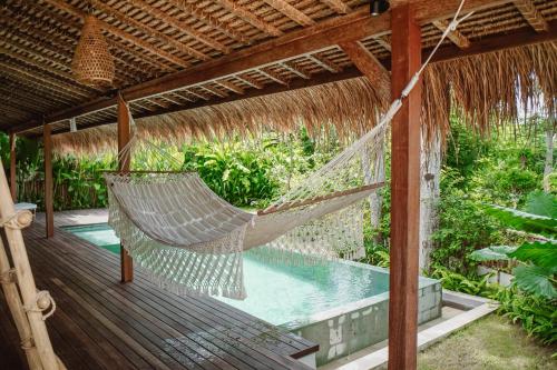 a hammock on a deck with a swimming pool at Gypsea Bali in Uluwatu