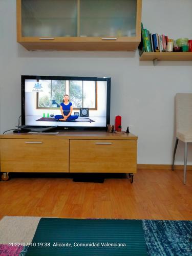 telewizor z płaskim ekranem na drewnianej komodzie w obiekcie Аlicante w Alicante