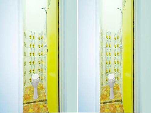 two urinals in a bathroom with yellow walls at OYO 91559 Kost Bangau Syariah in Perabumulih