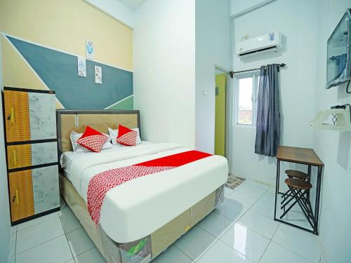 ein Schlafzimmer mit einem Bett und einem Tisch in einem Zimmer in der Unterkunft OYO 91559 Kost Bangau Syariah in Perabumulih