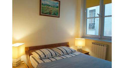 1 dormitorio con 1 cama con 2 lámparas y una ventana en Le 38, rue Saint-Louis en l'île en París