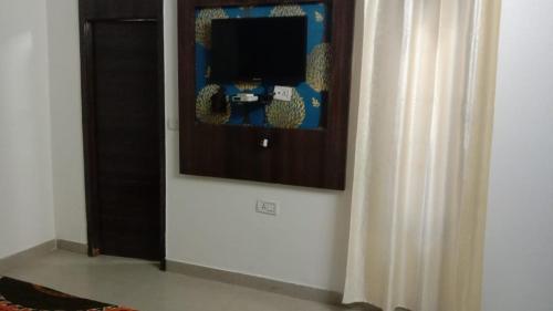 a living room with a tv and a curtain at Hotel Vanya Palace By WB Inn in Agra