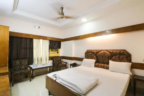 a bedroom with a large bed and a chair at Hotel Natraj in Bilāspur