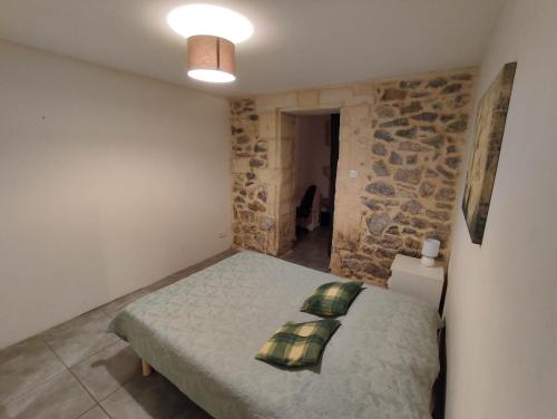 une chambre avec un lit et un mur en pierre dans l'établissement Pont De Crau, à Arles