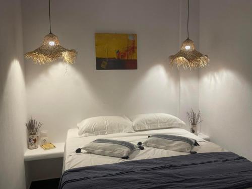 una camera da letto con un letto con due luci sopra di esso di Ονειρόπετρα Λέρος~Oneiropetra Leros a Panteli