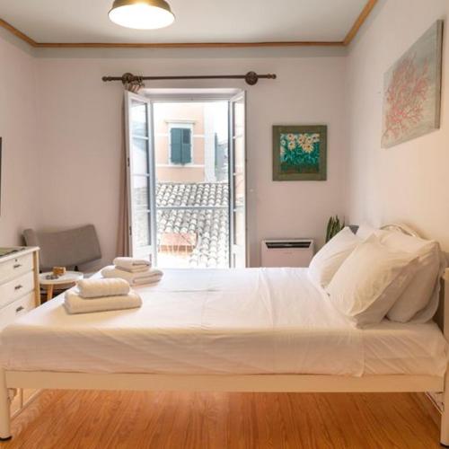 ein großes weißes Bett in einem Zimmer mit Fenster in der Unterkunft Nasos Corfu Town Apartment in Korfu-Stadt