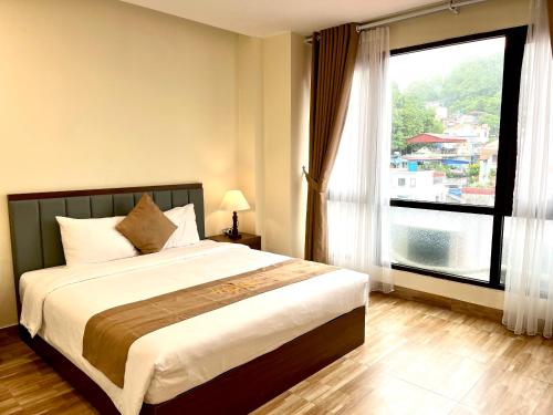 a bedroom with a large bed and a large window at CAT BA ROSALIA HOTEL in Cat Ba