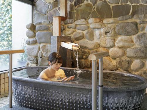 a child bathing in a hot tub in a stone wall at Aishinkan in Morioka