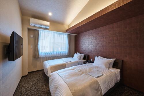 pokój hotelowy z 2 łóżkami i telewizorem w obiekcie HOTEL ARROWS ARASHIYAMA w mieście Kioto