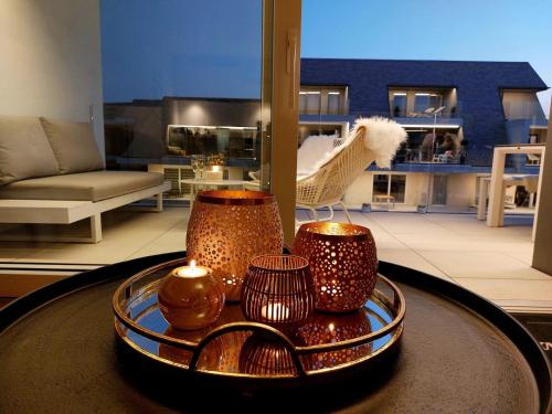 a table with three candles on top of a living room at Villa Creole 0308 Luxe appartement met verwarmd zwembad Nieuwpoort Jachthaven in Nieuwpoort