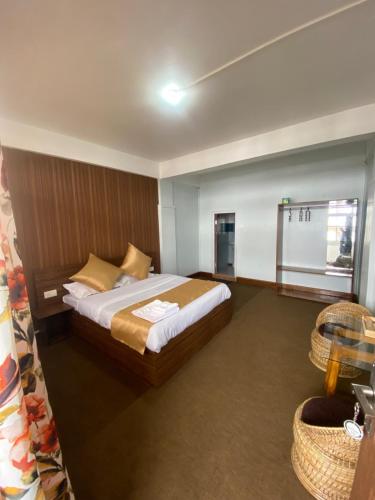 um quarto com uma cama grande e uma janela em The Valaya Hotel em Darjeeling