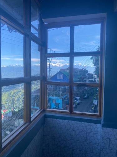 a room with four windows with a view of a city at The Valaya Hotel in Darjeeling