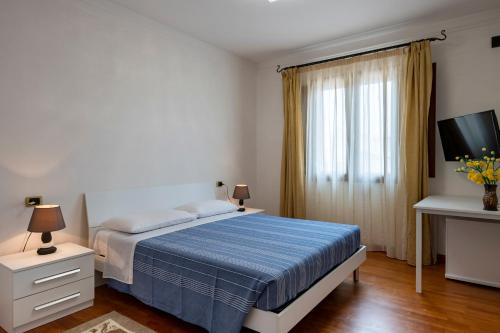 a bedroom with a bed and a tv and a window at Sa Omu Bianca in Tortolì