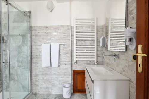 a white bathroom with a sink and a shower at Sa Omu Bianca in Tortolì