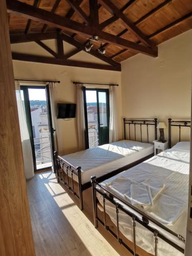 two twin beds in a room with windows at LaZaRTe in Mytilene