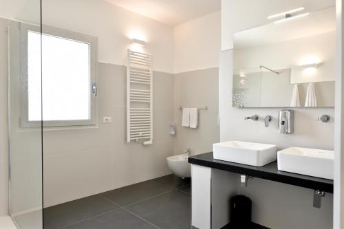 a white bathroom with two sinks and a mirror at Sa Omu Bianca in Tortolì