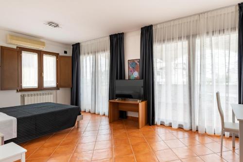 a bedroom with a bed and a table and windows at Sa Omu Bianca in Tortolì