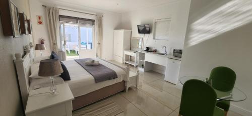 a bedroom with a bed with a desk and a kitchen at Paternoster Lodge in Paternoster