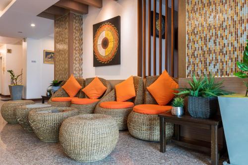a lobby with rattan furniture and orange pillows at 24@Home Hotel in Nonthaburi
