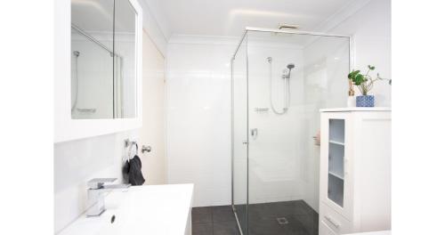 a white bathroom with a shower and a sink at The Lake House - Cabarita Beach in Cabarita Beach