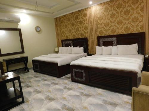 a hotel room with two beds and a television at Hotel SR Lounge Multan in Multan