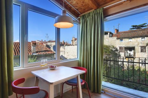 - une salle à manger avec une table, des chaises et de grandes fenêtres dans l'établissement Apartments Forum 2, à Pula