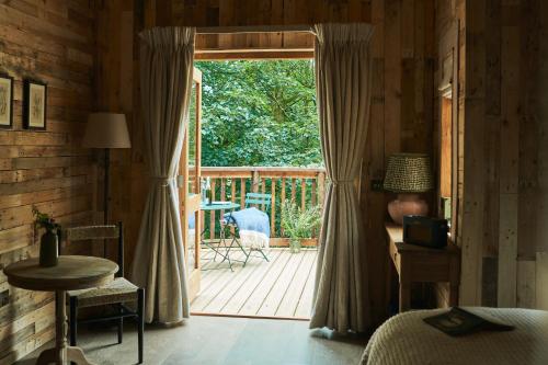 a bedroom with a door open to a porch with a deck at Wildhive Callow Hall in Ashbourne
