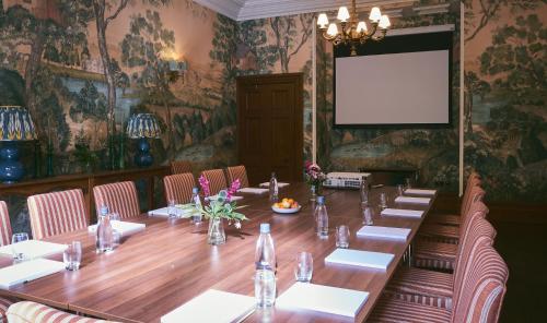 uma sala de conferências com uma mesa longa e um ecrã de projecção em Wildhive Callow Hall em Ashbourne