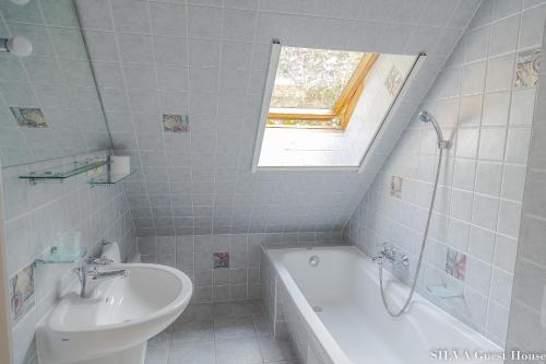 a white bathroom with a sink and a tub and a window at SILVA Guest House - dom wczasowy, tenis, basen, balia i sauna in Borsk