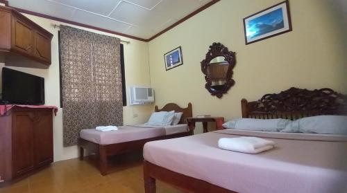 a hotel room with two beds and a tv at RF ANICETO MANSION in Vigan