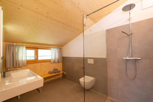 a bathroom with a shower and a toilet and a sink at Neusach64 in Weissensee