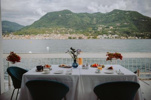a table with food and a view of the water at Ah Porticcioli Boutique Apartments in San Felice del Benaco