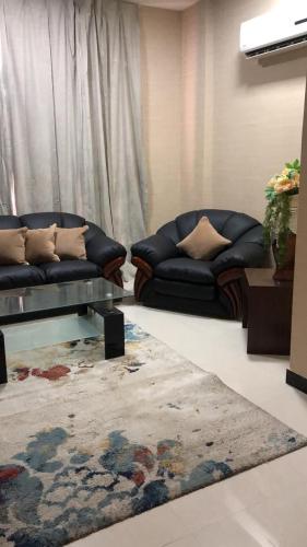 a living room with two couches and a rug at Alpha Suites Hotel in Salalah