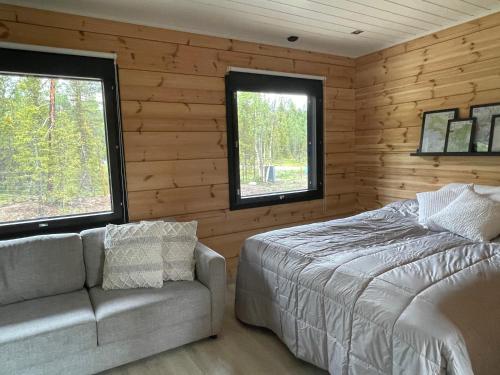- une chambre avec un lit, un canapé et deux fenêtres dans l'établissement Villa JoenPolku Ruka, à Ruka