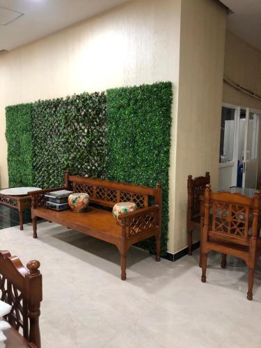 two benches sitting in front of a green wall at Alpha Suites Hotel in Salalah