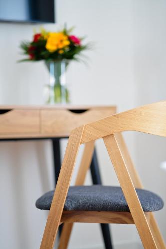 a wooden chair next to a table with a vase of flowers at Luma Terra Prague Hostel in Prague