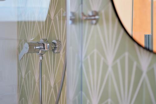 a glass door with a shower nozzle in a bathroom at Luma Terra Prague Hostel in Prague