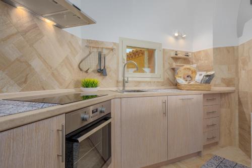 una cocina con armarios de madera y fregadero en Appartamento Smeralda - SHERDENIA Luxury Apartments en Marinella