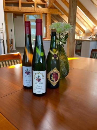 three bottles of wine sitting on a wooden table at Secret Hideaway with picturesque Sundown Views in Traben-Trarbach