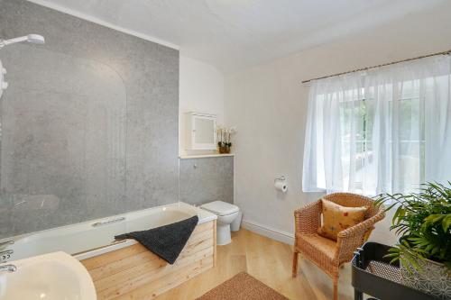 a bathroom with a tub and a toilet and a chair at Badger Cottage in Parkend