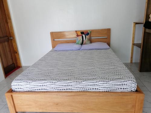 a bed with a wooden headboard in a room at Kathleens Vacation Place in Moalboal