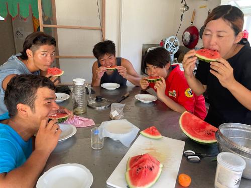 a group of people sitting at a table eating watermelon at ゲストハウス千倉のおへそ in Chikura