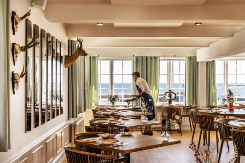 Ein Mann steht in einem Esszimmer mit Tischen. in der Unterkunft Hotel Siemsens Gaard in Svaneke